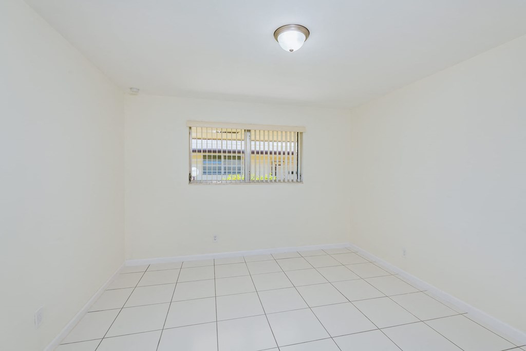 a empty room with a window and a white tiled floor