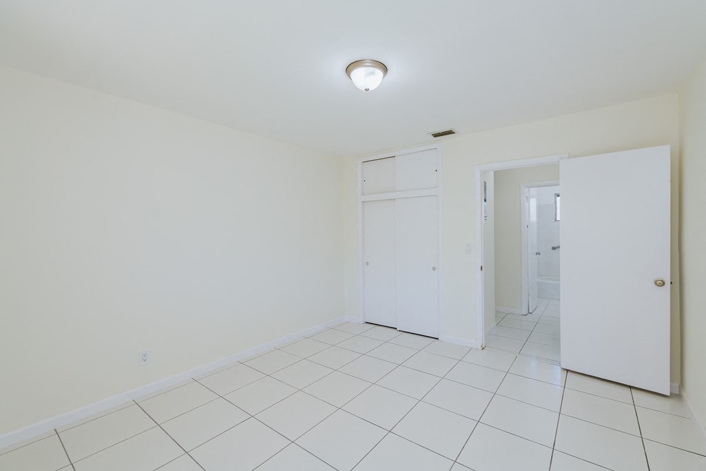 a room with a white tiled floor and a door to a closet