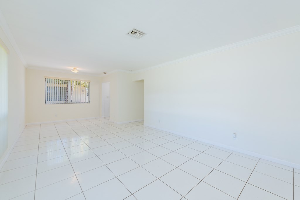 the living room and dining room of an empty house with white tiled flooring