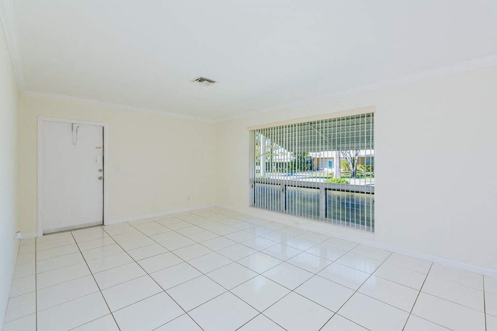 an empty living room with a large window and white tiles