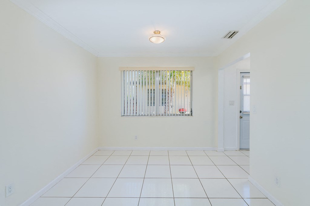 a white room with a window and a white tiled floor