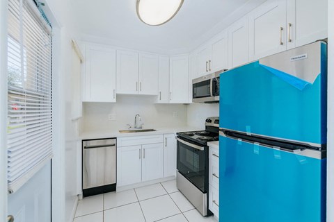 a kitchen with white cabinets and a blue refrigerator
