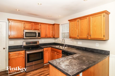 A kitchen with wooden cabinets and black countertops.