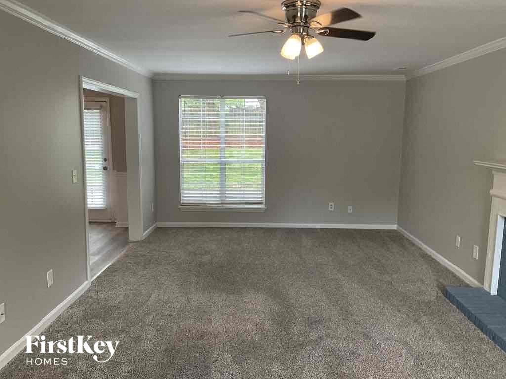 A room with a fan and a carpet on the floor.