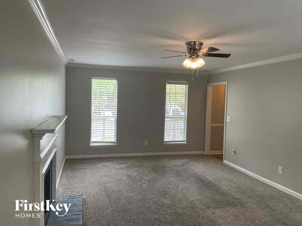 A room with a grey carpet and a ceiling fan.