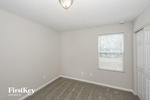 the spacious living room of an apartment with carpet and a window