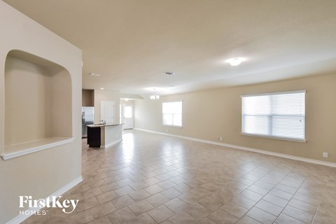 A spacious empty room with tile flooring and a large window.