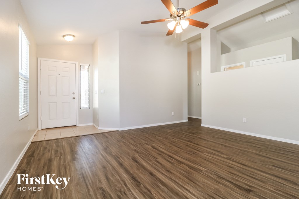 A spacious room with a ceiling fan and wooden flooring.