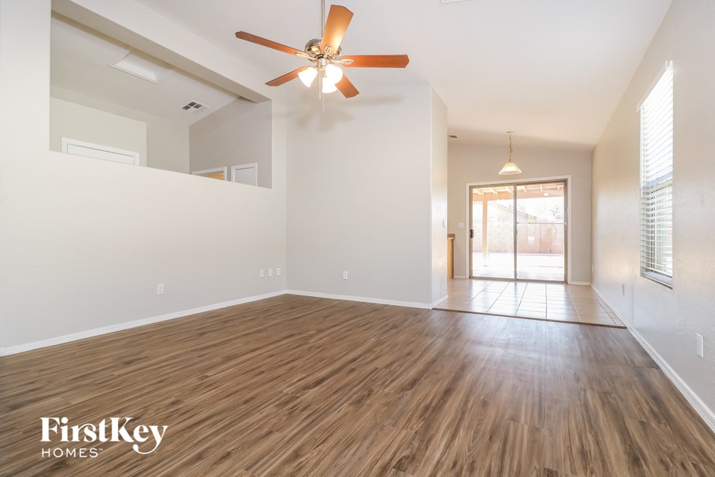 A spacious room with wooden flooring and a ceiling fan.