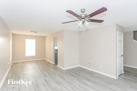 A spacious room with a ceiling fan and lighting fixture.