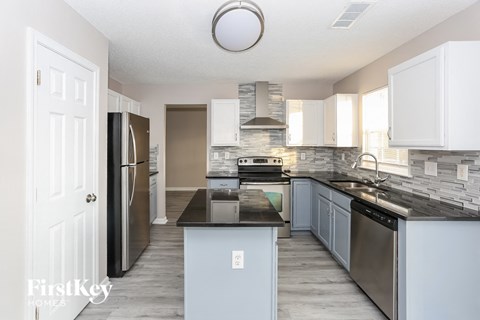 A kitchen with a black countertop and stainless steel appliances.
