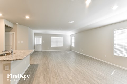 A spacious room with wooden flooring and a kitchen area with a sink.