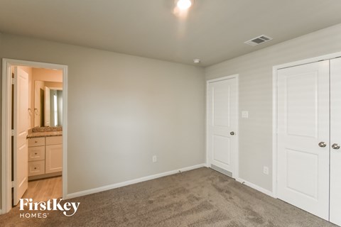 A bedroom with a carpeted floor and a white door.