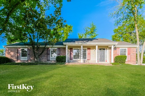 a small brick house with a lawn and trees