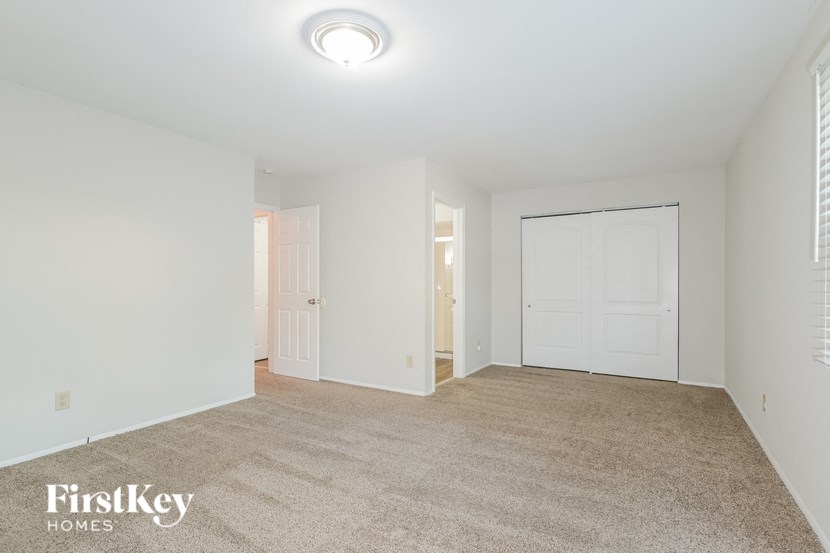 a master bedroom with a carpeted floor and a door to a closet