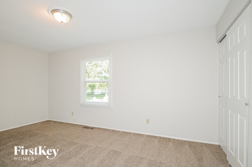 a bedroom with white walls and carpet and a window