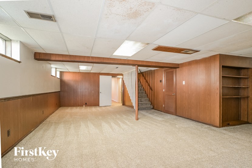 a living room with a staircase and wood paneling