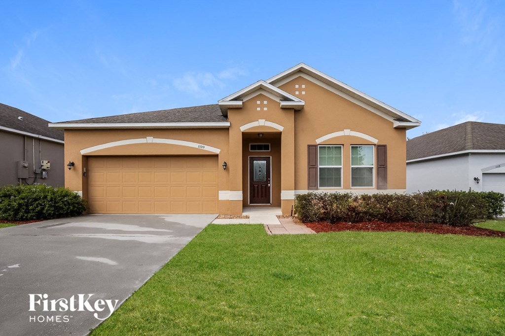 a beige house with a garage door and a lawn