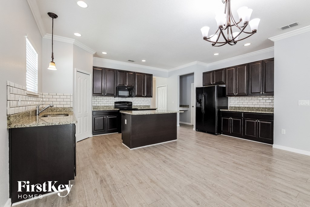 a renovated kitchen with black appliances and wood flooring