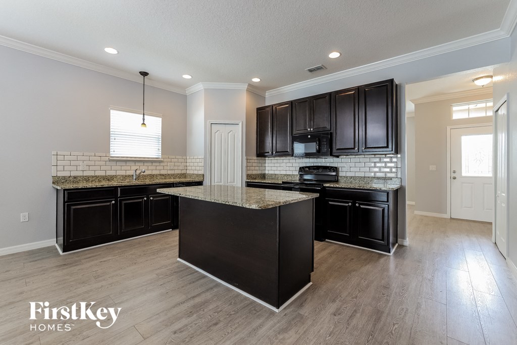a kitchen with black cabinets and granite counter tops