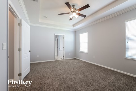 a living room with a ceiling fan and a carpet
