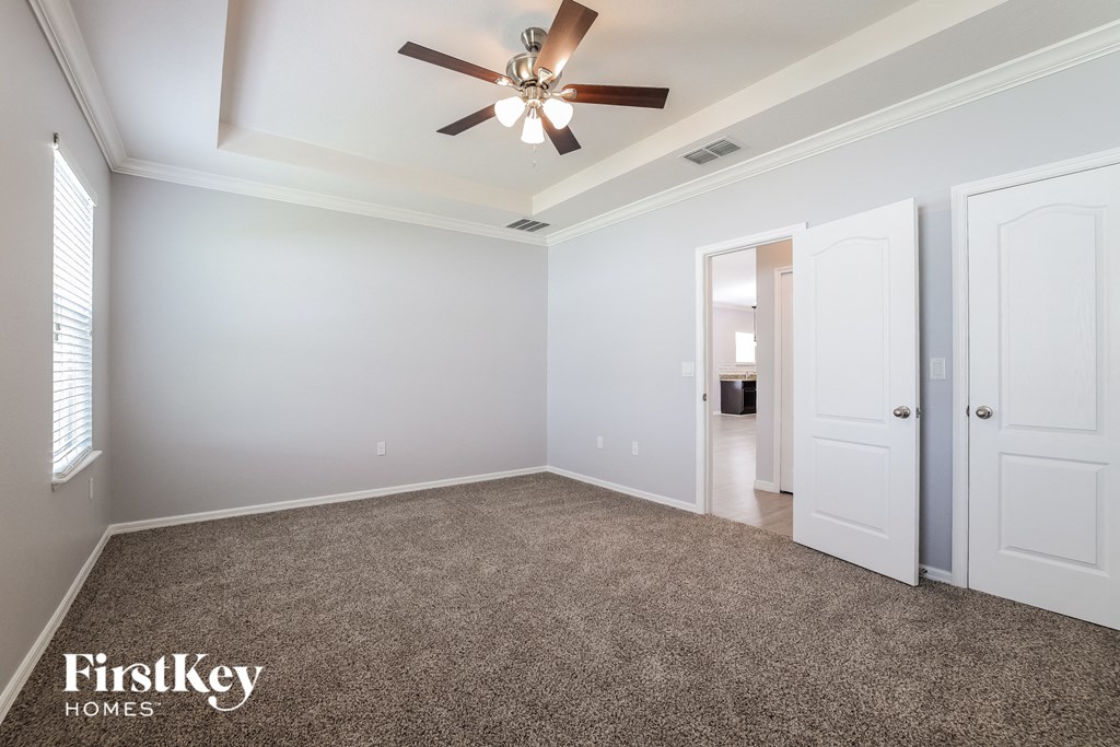 a empty living room with a ceiling fan and white doors
