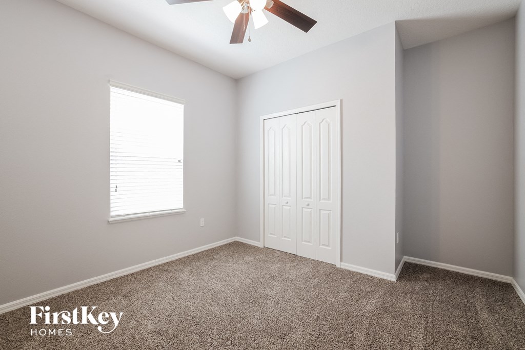 a bedroom with a ceiling fan and a closet