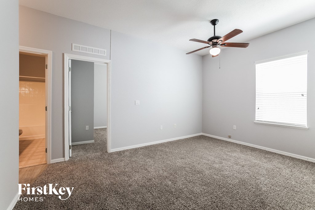 a bedroom with carpet and a ceiling fan and a door to a closet