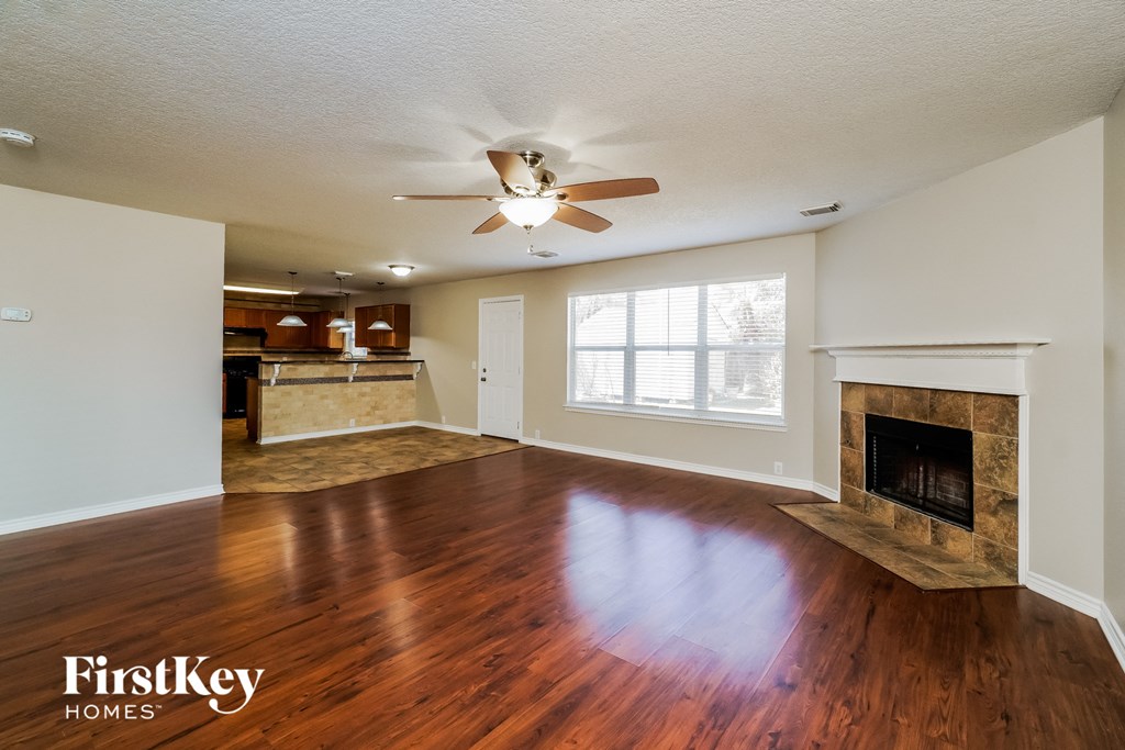 an empty living room with a fireplace and a ceiling fan