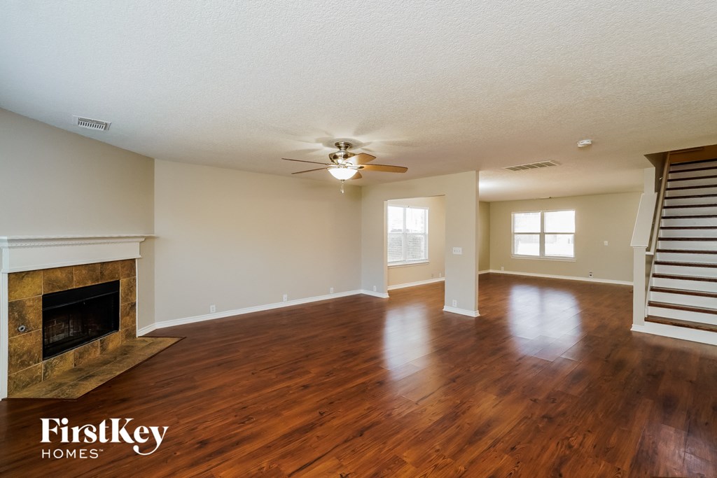 an empty living room with a fireplace and a ceiling fan