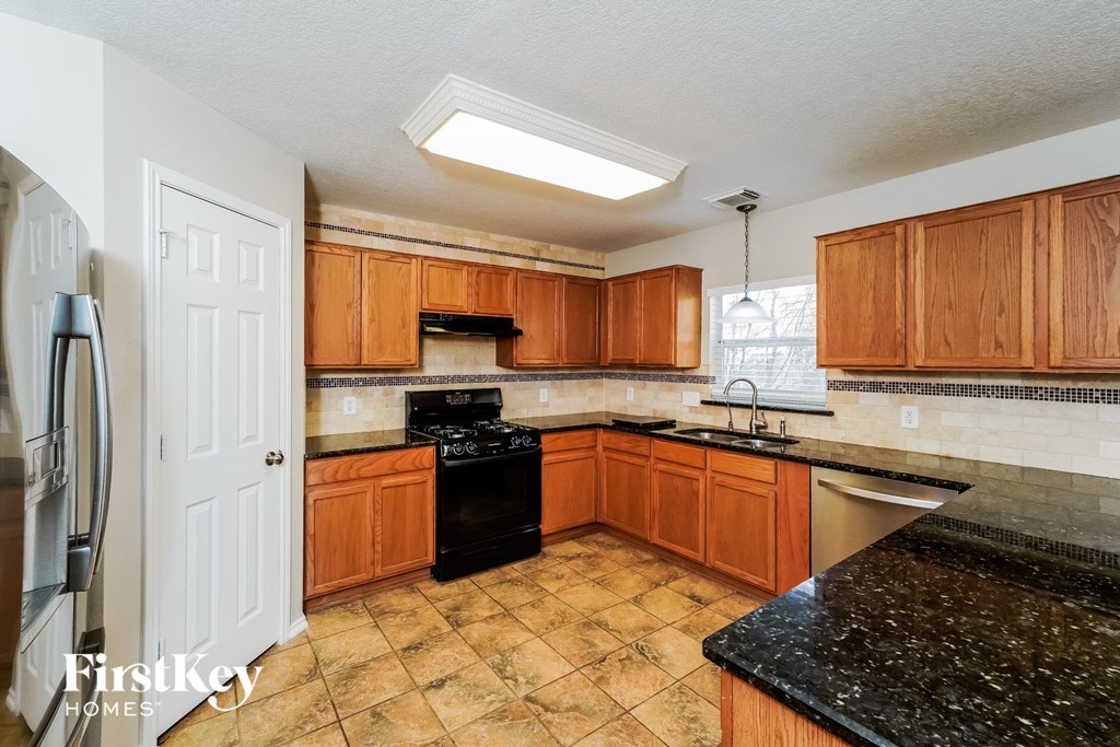 a kitchen with wooden cabinets and black counter tops