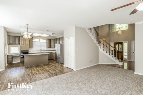 an open kitchen and living room with a staircase and a kitchen island