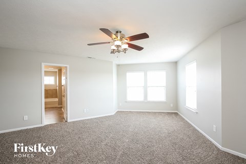 the master bedroom has a ceiling fan and carpet