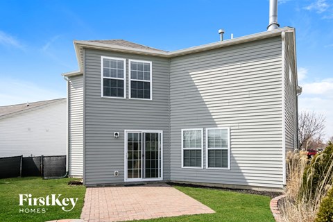 the outside of a grey house with a driveway and grass