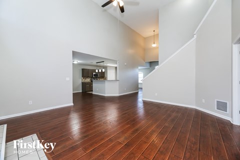 A spacious room with wooden floors and a staircase leading to another room.