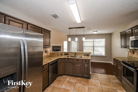 A kitchen with a stainless steel refrigerator and brown cabinets.