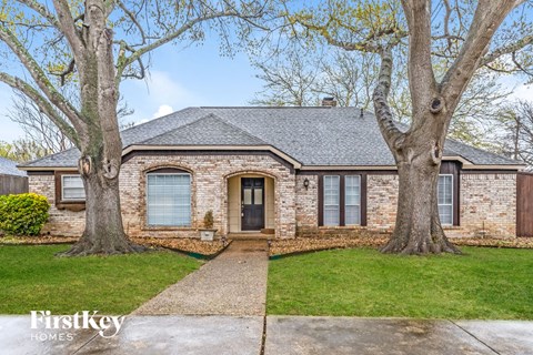 front view of a brick house with two trees