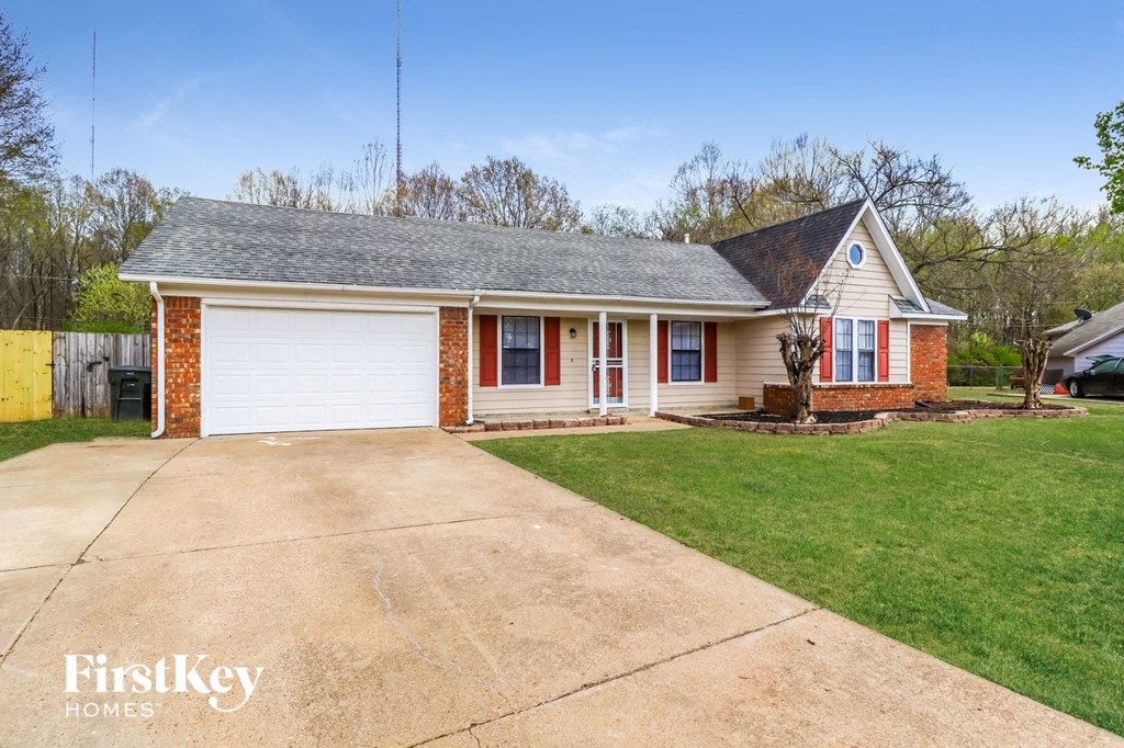a white and red brick house with a driveway and grass
