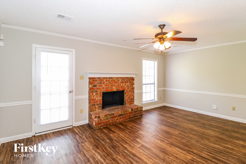the living room of a house with a fireplace and a ceiling fan