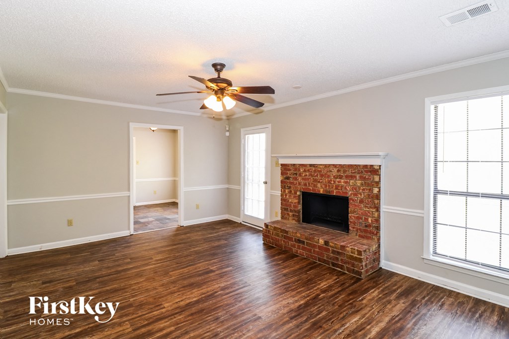 a living room with a brick fireplace and a ceiling fan
