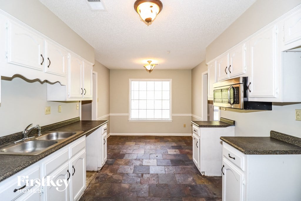 a kitchen with white cabinets and a sink and a window