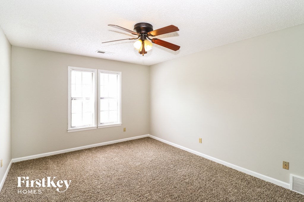 the master bedroom has a ceiling fan and a carpet