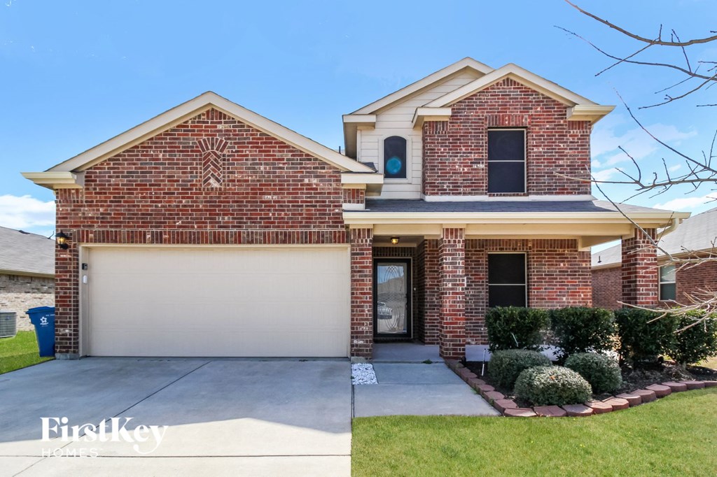 A brick house with a garage door and a small front yard.