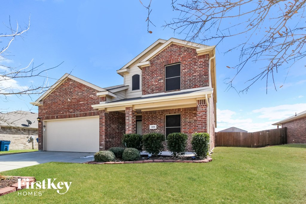 A brick house with a garage door and a tree branch in the foreground.