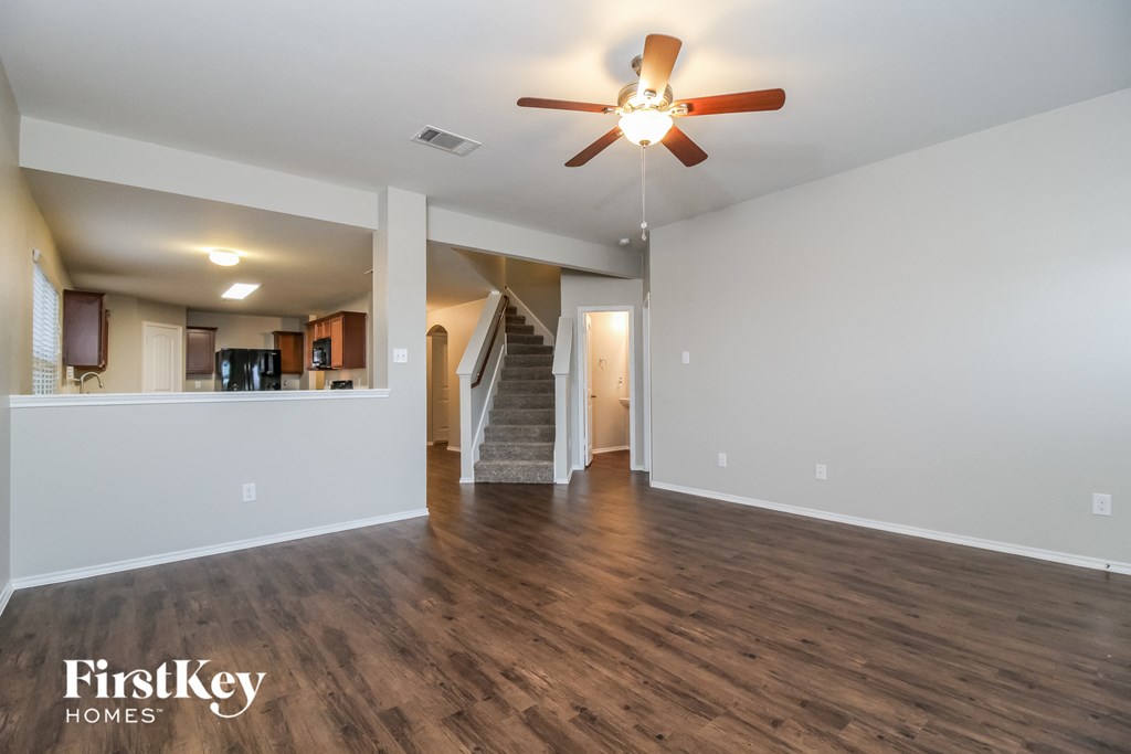 A spacious room with a ceiling fan and wooden flooring.