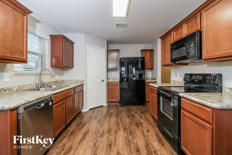 A kitchen with wooden cabinets and a black refrigerator.