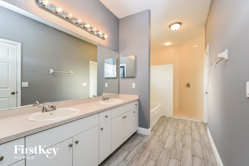 the master bathroom has dual sinks and a large mirror