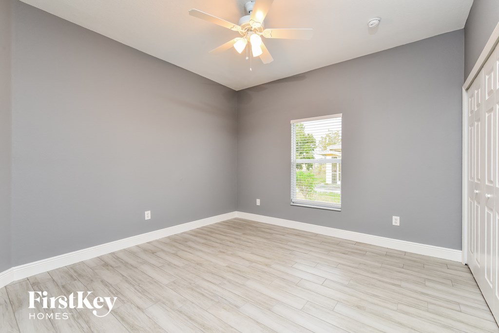 an empty room with a ceiling fan and a window