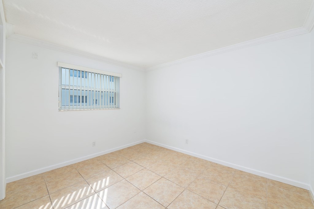 an empty living room with a window and a tiled floor