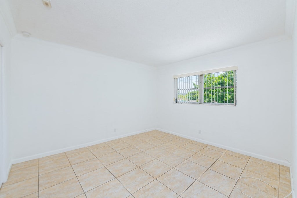 an empty living room with tiled floor and a window